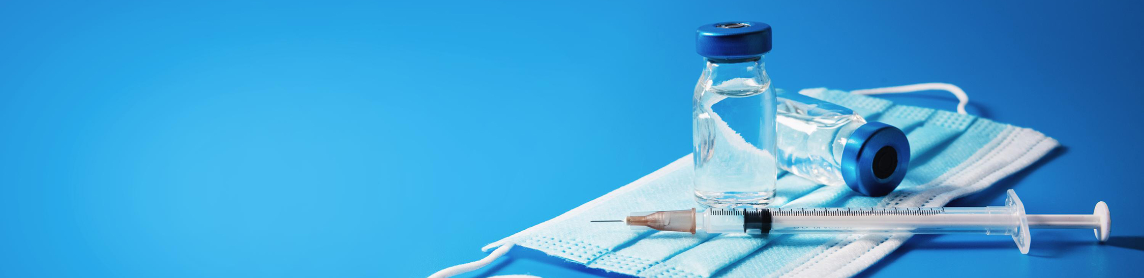 blue background with mask, needle and vital placed on the side