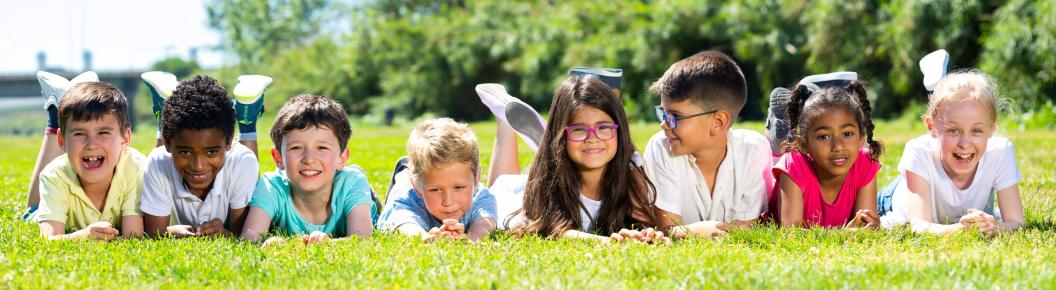 "Group of diverse children posing together outdoors on grass"