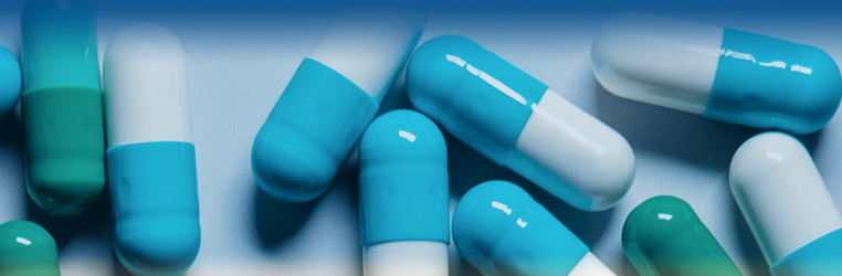 Close-up of blue and white capsules on a light blue surface.