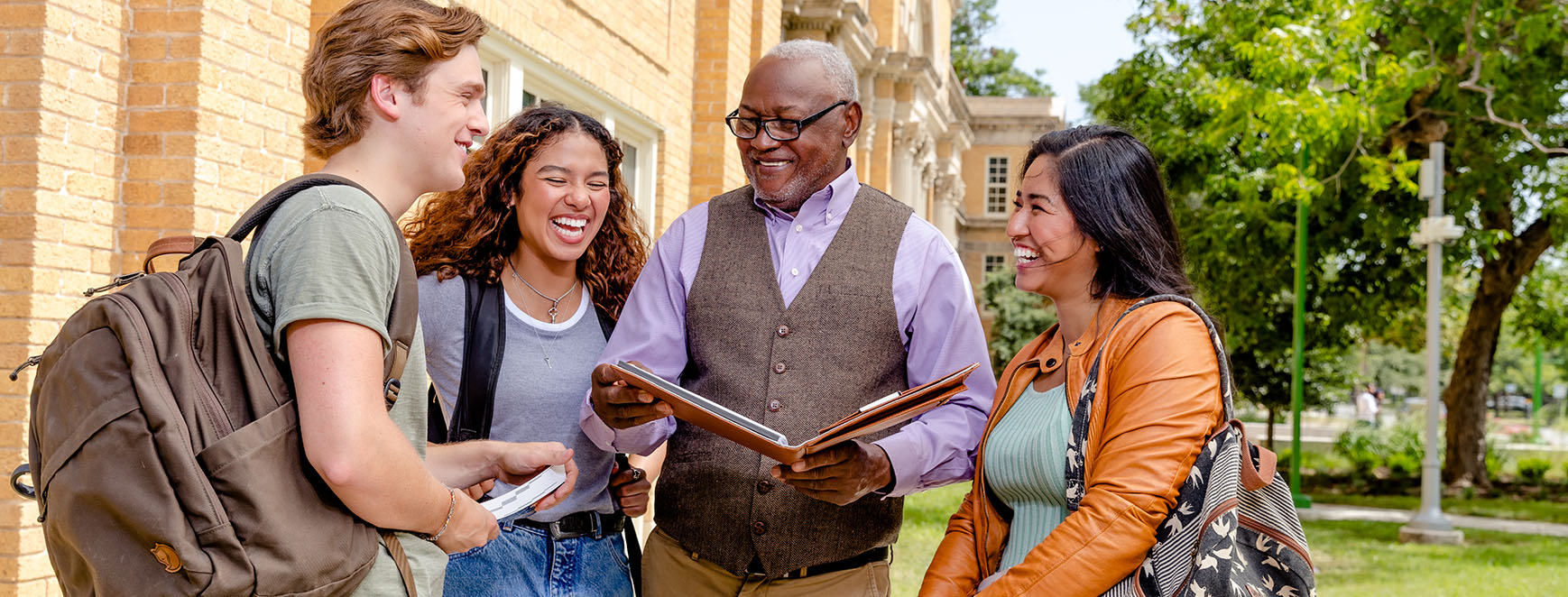 three college students with professor outside