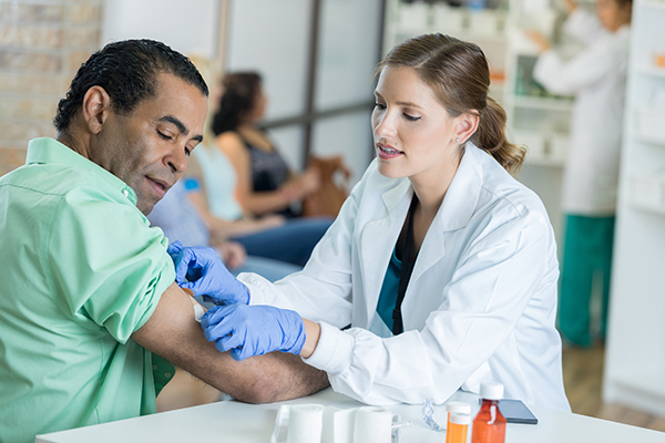 Doctora colocando una curita en el brazo derecho de un paciente hombre
