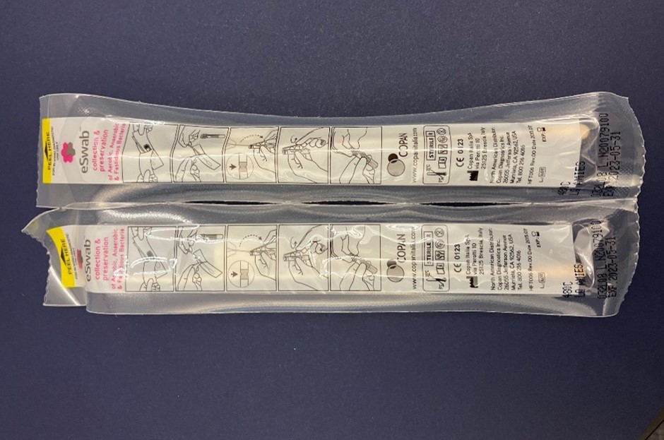 "An overhead image of the top side of  two sealed, unopened ESwab Collection Kits for Candida clinical specimen collection.  Kit expiration dates are visible at the bottom of the swab packets. "
