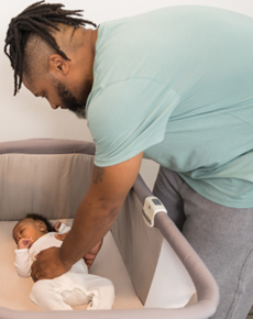 photo of a father putting a baby in the crib