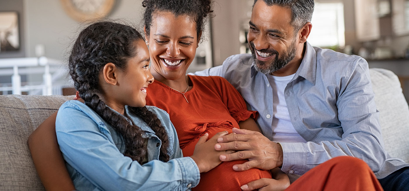 A man and child sitting with a pregnant woman.