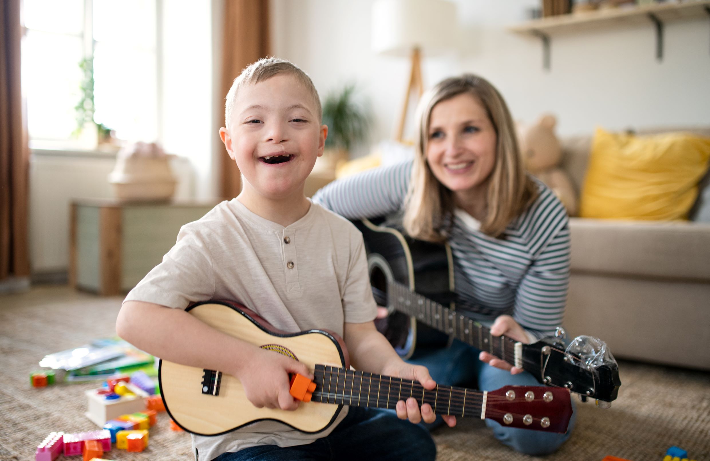 Mom and child with down syndrome playing guitar.