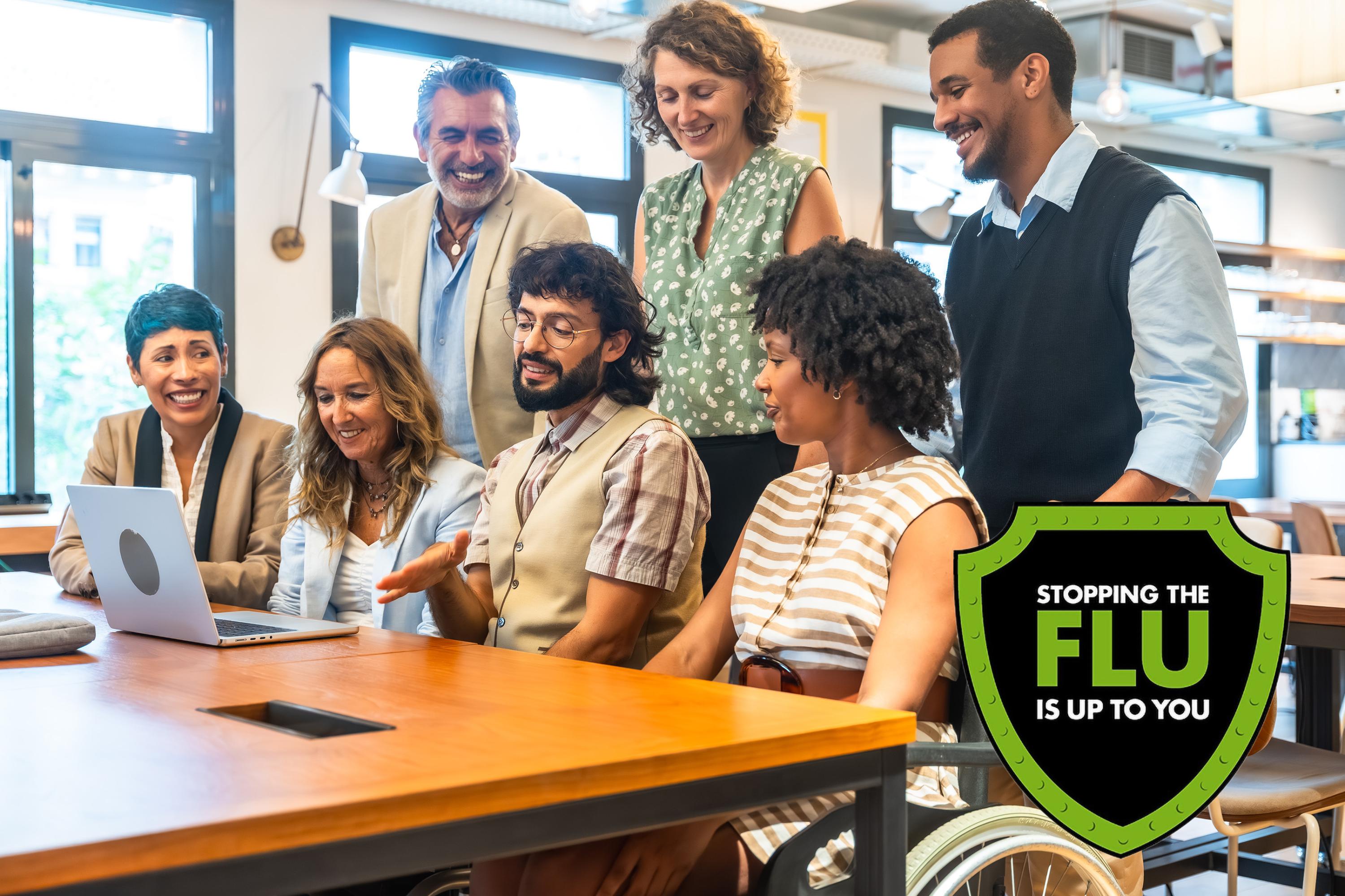 A diverse group of people sitting around a laptop next to a green and white shield icon that reads "Stopping the Flu is up to you".