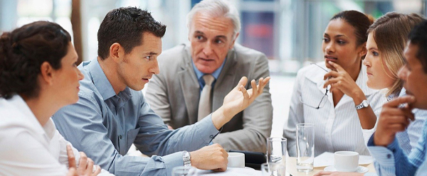 People gathered around a meeting table in discussion.
