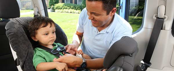 Man buckling a child into a car seat.