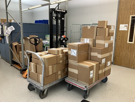 A cart stacked with several taped up and labeled cardboard boxes.
