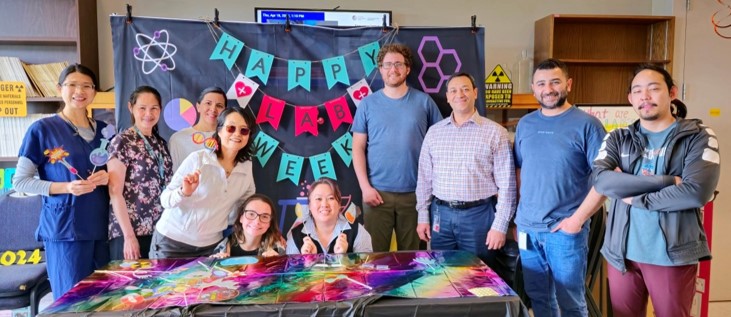 A group of 10 people posing for a photo in front of a backdrop 