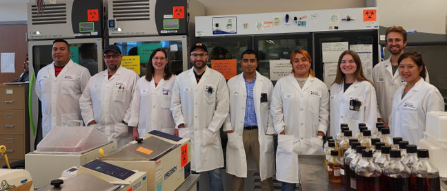 A group of nine people in lab coats, smiling.