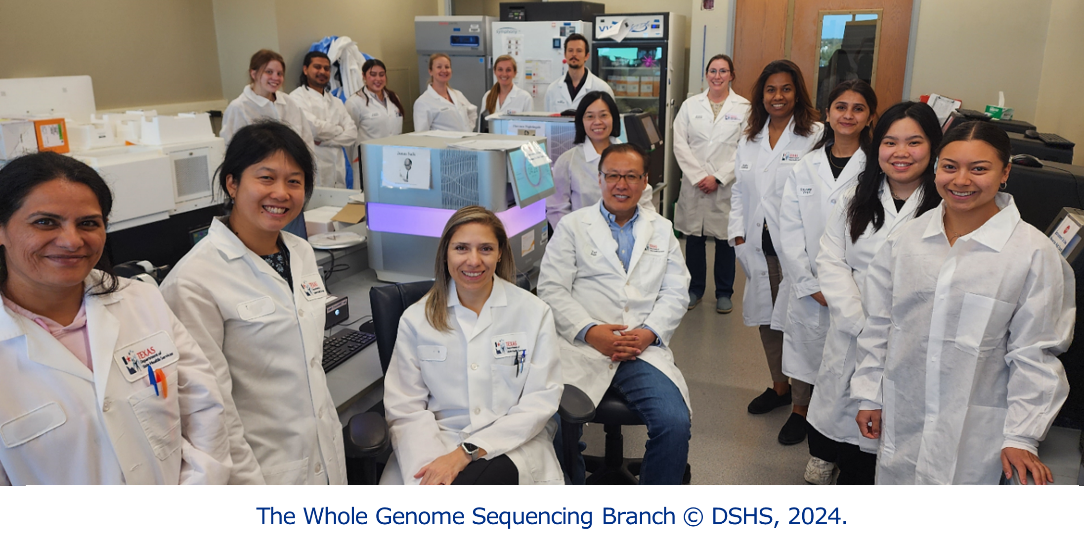A group of smiling people wearing lab coats who are  in a laboratory