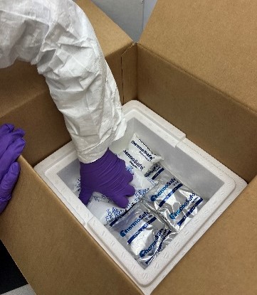 A person in a white protective suit opening a box