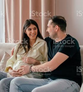 Pregnant woman and man sitting on a couch.