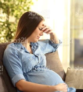 Pregnant woman sitting on a couch, not feeling well. 