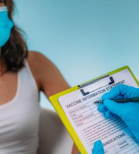 Woman with a mask going over a vaccine information statement