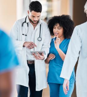 Male doctor discusses chart with female doctor in blue scrubs