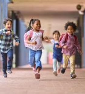 Group of multiethnic young children running down the hallway