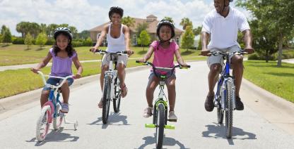 A family rides their bike down the street.
