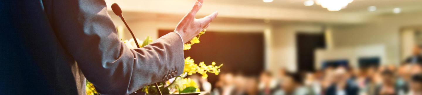 Unrecognizable businessman making a speech in front of audience at conference hall stock photo.
