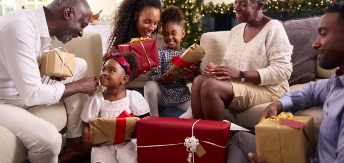 Familia intercambiando regalos en una sala de estar decorada para las fiestas.