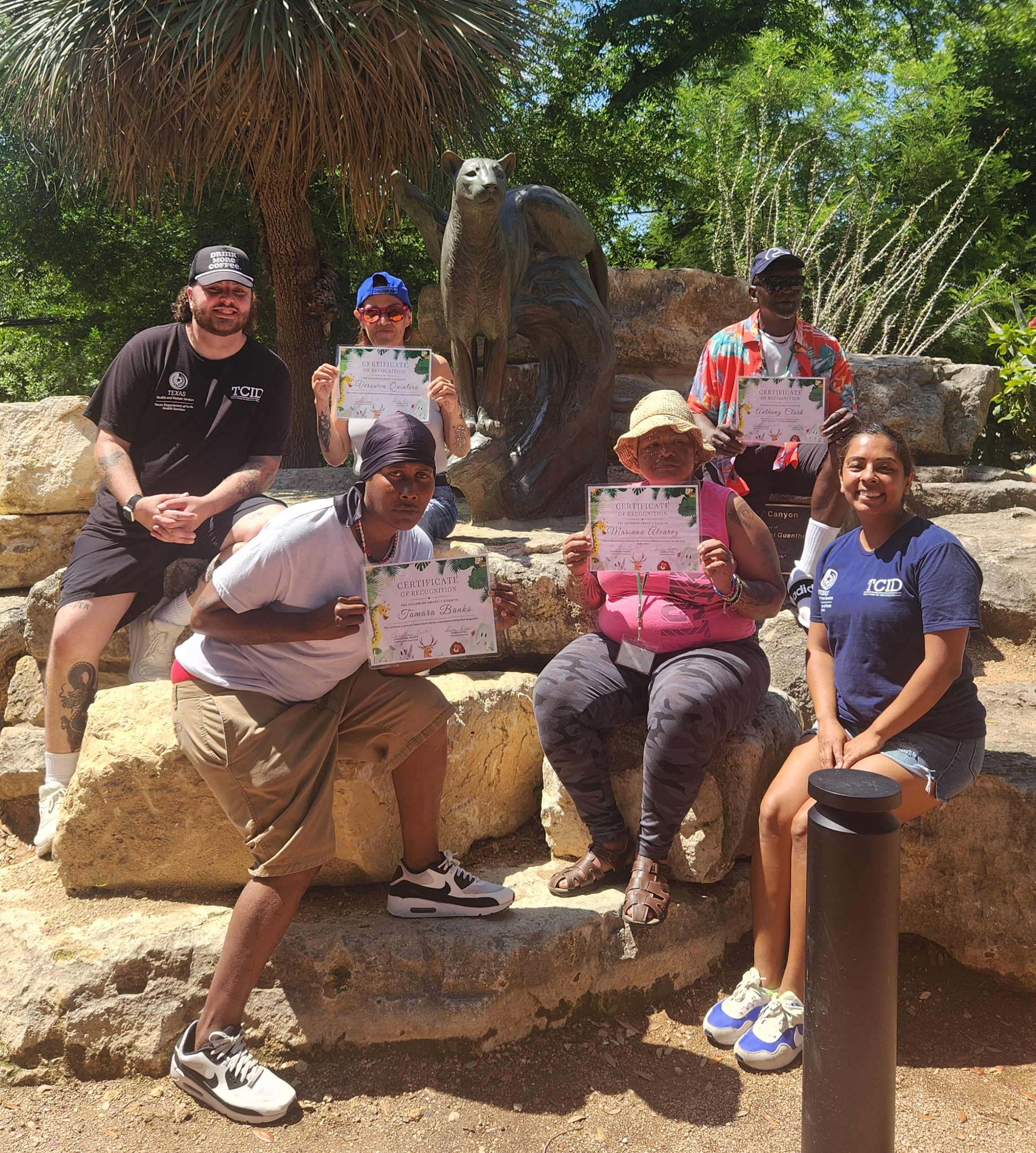 A group of patients hold up certificates in front of an animal statue
