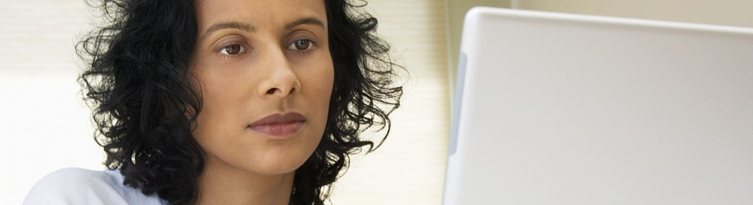 White woman with curly hair looking at laptop screen, decorative