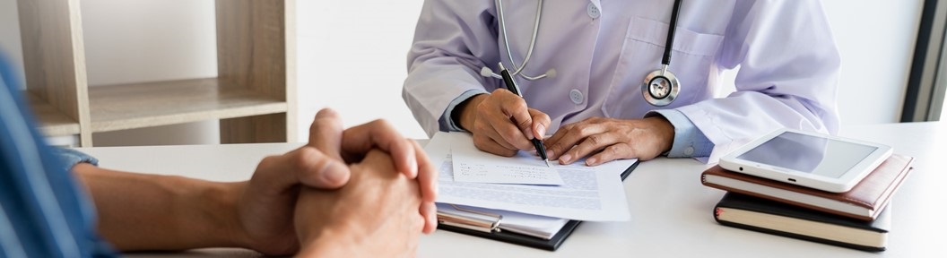 Close up of the hands of one person facing a doctor sitting opposite, decorative