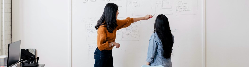 Two women looking at a dry erase board, decorative