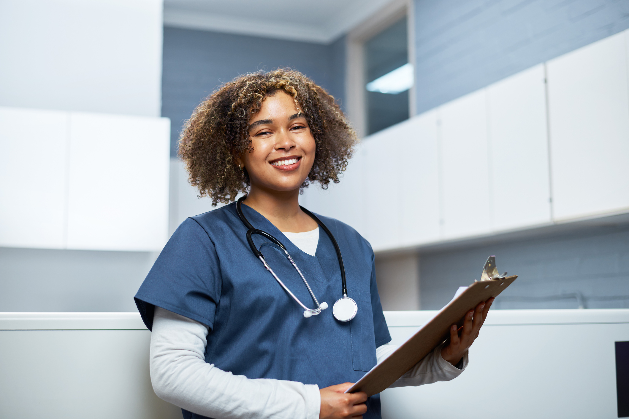 Woman nurse smiling and holding a clipboard