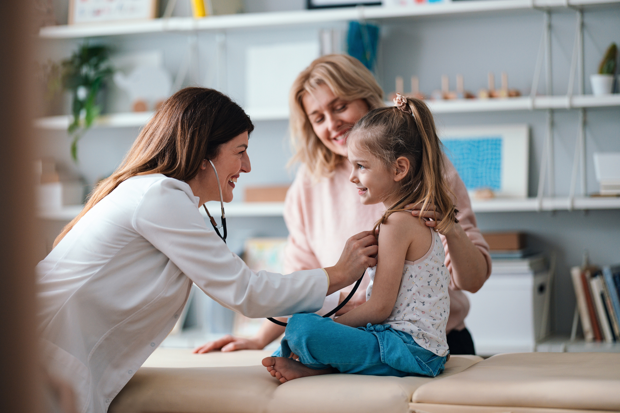 Woman doctor with daughter and mother performing a check up on the daughter.