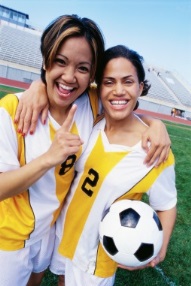 Two girls posing with soccer ball